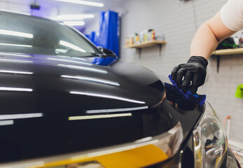 Car detailing - Man applies nano protective coating to the car. Selective focus.