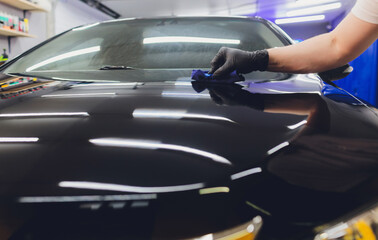 Car detailing - Man applies nano protective coating to the car. Selective focus.