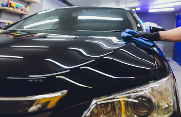 Car detailing - Man applies nano protective coating to the car. Selective focus.