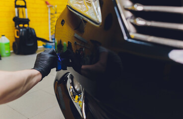 Car detailing - Man applies nano protective coating to the car. Selective focus.
