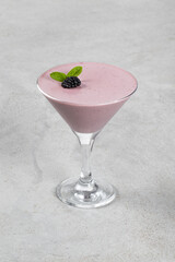 Italian dessert. Blackberry cream jelly, Panna Cotta in a martini glass. Light background	