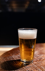 Pint glass of cold fresh british ale and lager beer served in old vintage English pub