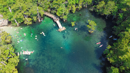 White sandy entrance and boardwalk ramp, deck jumping to magnitude turquoise blue water of Morrison Springs County Park in Walton County, Florida, USA surrounded by lush bald cypress tree