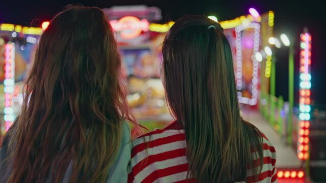Closeup fun friends resting colourful amusement luna park. Two girls hang out
