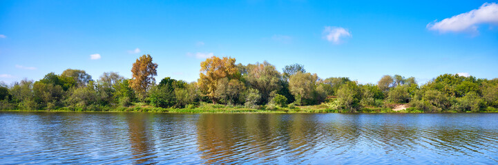Panoramic view of the river and forest against the blue sky on a clear sunny day