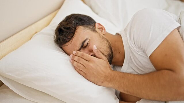 Young hispanic man lying on bed crying at bedroom