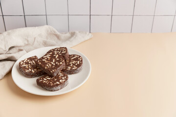 Traditional portuguese dessert Salame de Chocolate on beige background in minimal style. Homemade cocoa cake.
