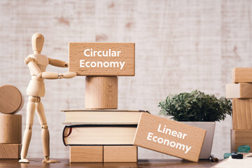 There is wood block with the word Circular Economy or Linear Economy. It is as an eye-catching...