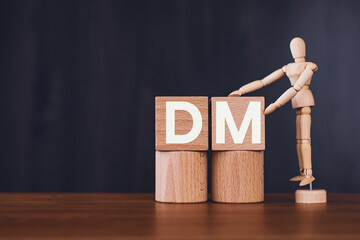 There is wood cube with the word DM. It is an abbreviation for Direct message as eye-catching image.