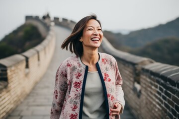 Obraz premium Lifestyle portrait photography of a grinning woman in her 30s that is wearing a chic cardigan at the Great Wall of China in Beijing China