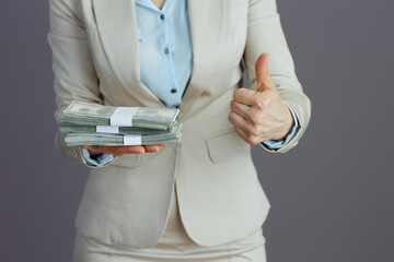 Business owner woman in light business suit showing thumbs up