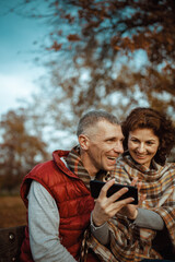 smiling romantic family in park using smartphone