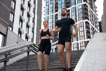 Obraz premium Healthy lifestyle. Happy couple running on steps outdoors, low angle view