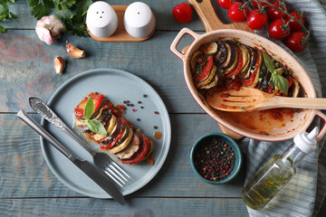 Delicious ratatouille served with basil on grey wooden table, flat lay