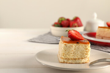 Piece of cheesecake with strawberry and fork on white table, closeup with space for text