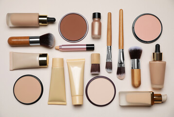 Face powders and other makeup products on beige background, flat lay