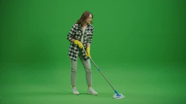 Green Screen.A Smiling Young Woman Housewife in Yellow Rubber Gloves is Washing the Floor with a Mop.Cleaning for Pet Allergies and Sensitivities.
