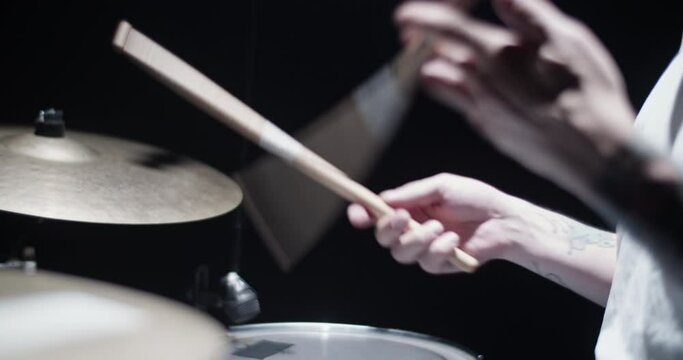 Crop anonymous musician spinning drumsticks on stage