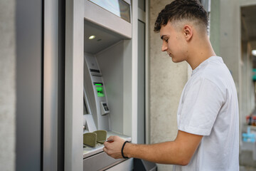 Naklejka na ściany i meble man teenage student using credit card and withdraw cash at the ATM