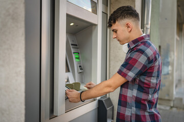 Fototapeta na wymiar man teenage student using credit card and withdraw cash at the ATM