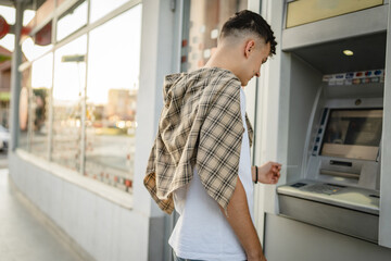 man teenage student using credit card and withdraw cash at the ATM - obrazy, fototapety, plakaty