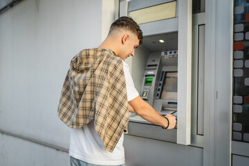 man teenage student using credit card and withdraw cash at the ATM