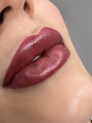 permanent makeup on the lips of a young woman of a delicate peach shade close-up, a girl after a cosmetic procedure with smooth and clean healthy skin.