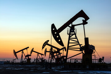 In the evening, oil pumps are running, Silhouette of beam pumping unit - obrazy, fototapety, plakaty