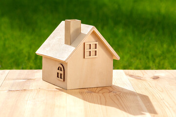 Ecological concept plot with wooden miniature house on nature background under sunlight