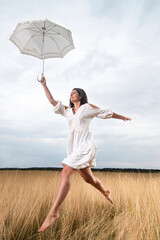 Young fiancee jumps for joy with a dress left out on the meadow