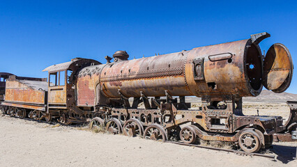 Fototapeta na wymiar Abandoned train cemetery with 100-year-old steam locomotives in Uyuni (Bolivia). They were used by mining companies in the 1900.