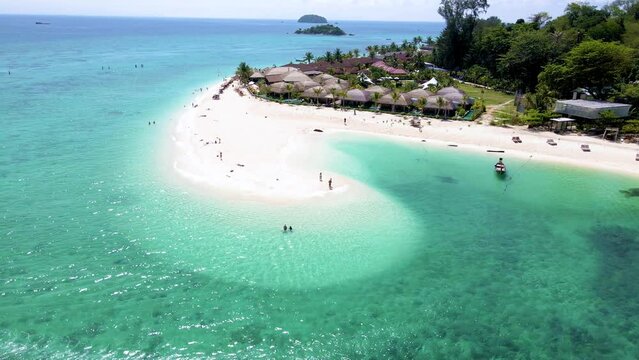Koh Lipe Island Thailand, is a tropical Island with a blue ocean and soft white sand. men and women relaxing on the beach at a sandbank looking out over the ocean
