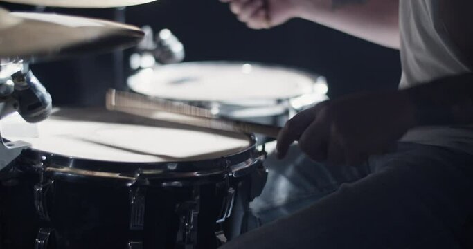 Crop faceless musician playing drums on stage