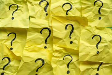 Questions and answers concept QnA. Yellow and crumpled memo note written with questions symbol.