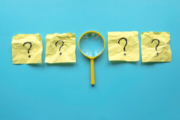 QnA or questions and answers concept. Yellow magnifying glass with question symbol on memo note...