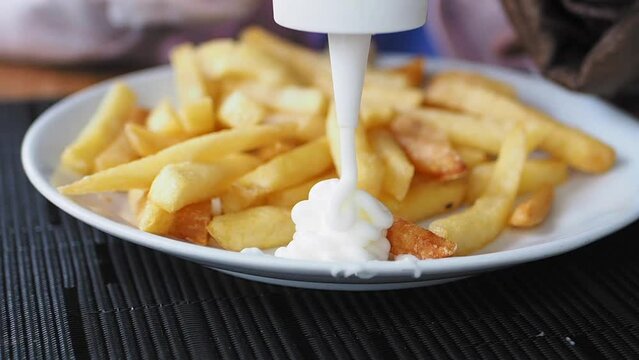 pouring Mayonnaise and French Fries served on a plate 