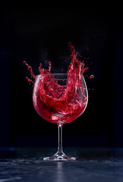 Glass of red wine with Red wine splash on dark background, Red wine splashes out of a glass, Beautiful red splash.,