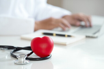Red heart and black stethoscope on white table. health care love, give, hope, and family concept,...