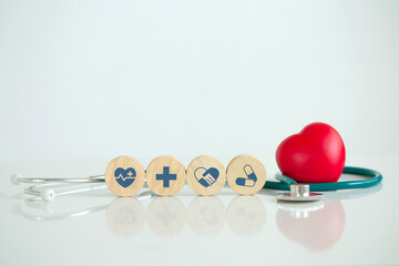 Wooden cubes with a blue health icon and Red heart and stethoscope on a white table, health...