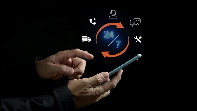Businessman hand using smartphone with hologram of 24/7 icons concept for contact customer service 24 hours 7 days. Call center landing page. Online support center for answers to customer questions.