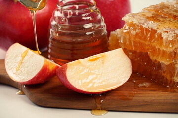 Jewish holiday Rosh Hashana celebration. Pomegranate, apples and honey traditional products for the holyday. Pouring honey on apple and pomegranate