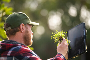 scientist agronomist farmer looking at soil samples and grass in a field in spring. looking at...