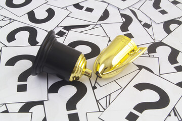 Broken golden  champion trophy cup on question marks background.