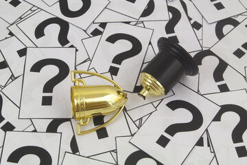 Broken gold champion cup on question marks background.