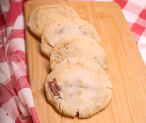 Savor the rich flavors of El Salvador with pupusas, a traditional Central American dish, served with curtido and savory sauce on a rustic wooden board