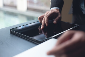 Businessman manager using digital tablet, finger touching on tablet screen, browsing the internet with laptop computer on table, close up. Business man working on computer at modern office