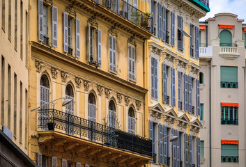 Fototapeta na wymiar Ornate Mediterranean house facades along a beautiful pedestrian street decorated with flowers in Nice on the French Riviera, South of France