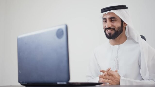 Handsome man with dish dasha working in his business office of Dubai. Portraits of a successful businessman in traditional emirates white dress. Concept about middle eastern cultures