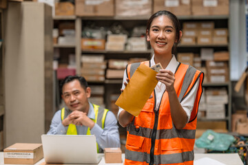 Young warehouse woman worker happy with salary cash bonus money from hard working in inventory...