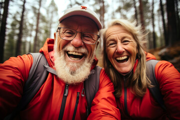 Portrait of happy senior cheerful active smiling mature couple hiking with backpacks, look happy in forest in afternoon autumn day time, happily retired. Elderly couple healthy lifestyle concept - obrazy, fototapety, plakaty